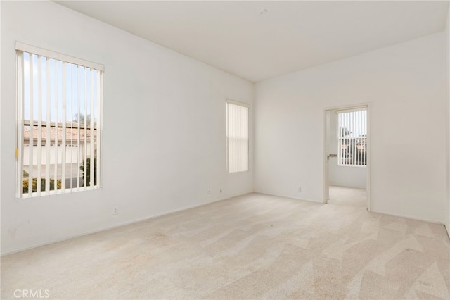 spare room with plenty of natural light and light colored carpet