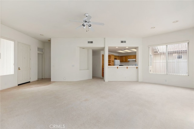 unfurnished living room featuring ceiling fan and light colored carpet