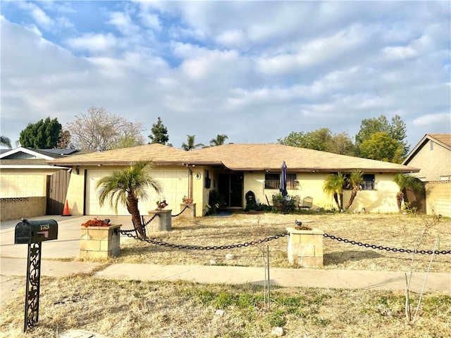 ranch-style house with a garage, driveway, and stucco siding