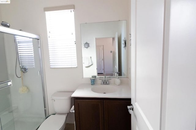 bathroom with vanity, a shower with door, and toilet