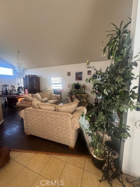 living room featuring a chandelier, light tile patterned flooring, and vaulted ceiling