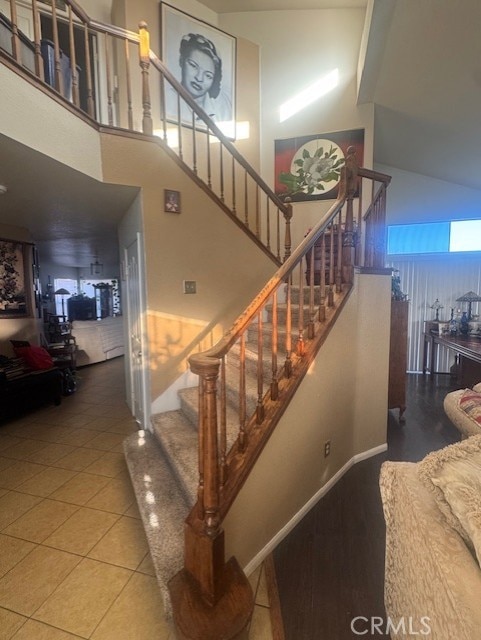 stairs featuring tile patterned flooring and a towering ceiling