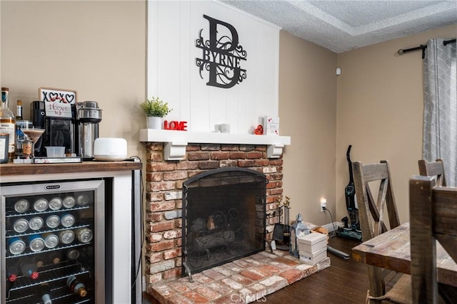 living room with dark hardwood / wood-style floors, beverage cooler, a textured ceiling, and a fireplace