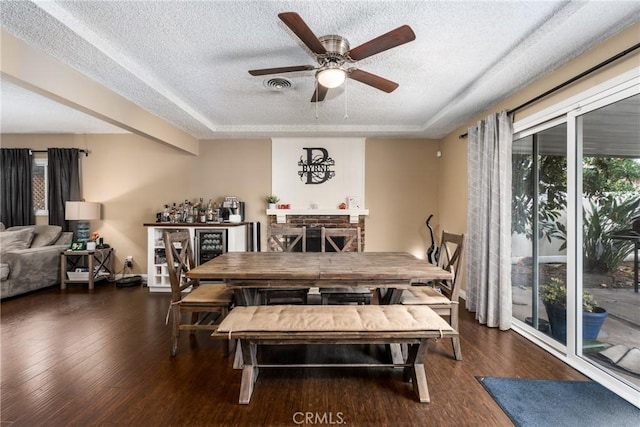 dining space featuring ceiling fan, dark hardwood / wood-style floors, a raised ceiling, and a textured ceiling