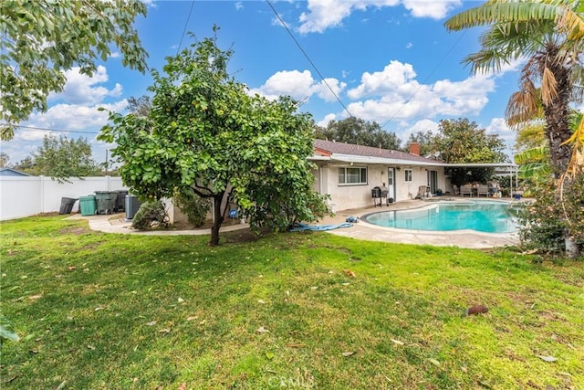 rear view of property featuring a fenced in pool, a lawn, and a patio