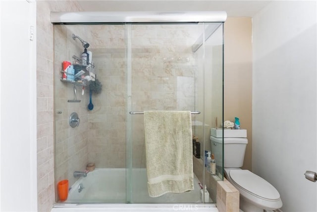 bathroom with bath / shower combo with glass door and toilet