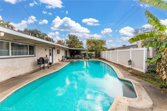 view of swimming pool with grilling area and a patio area