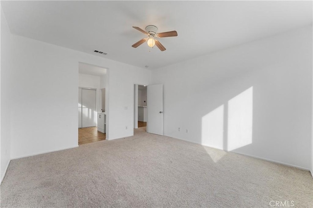 unfurnished bedroom with light carpet, connected bathroom, a spacious closet, and ceiling fan