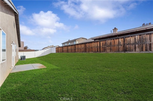 view of yard with a fenced backyard and central AC unit