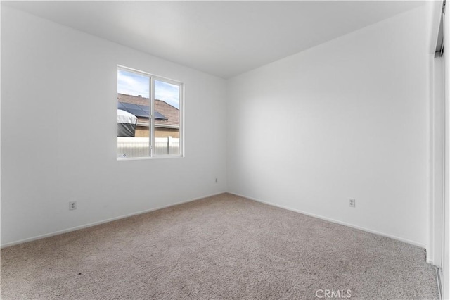 carpeted empty room featuring baseboards