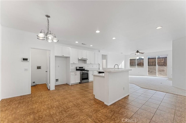 kitchen featuring light countertops, hanging light fixtures, open floor plan, stainless steel range oven, and white cabinetry