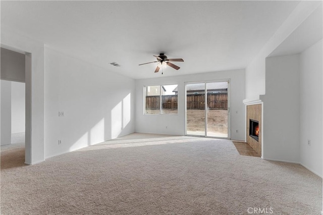 unfurnished living room with a ceiling fan, visible vents, a fireplace, and light carpet