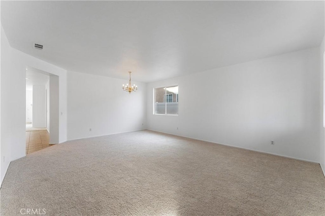 carpeted spare room with a notable chandelier