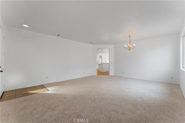 carpeted empty room featuring a notable chandelier