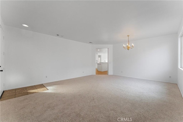 carpeted spare room with visible vents and a notable chandelier