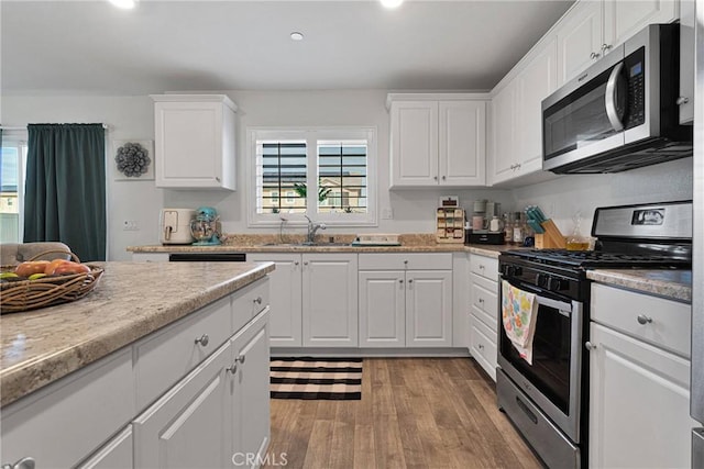 kitchen featuring white cabinetry, appliances with stainless steel finishes, sink, and light hardwood / wood-style flooring