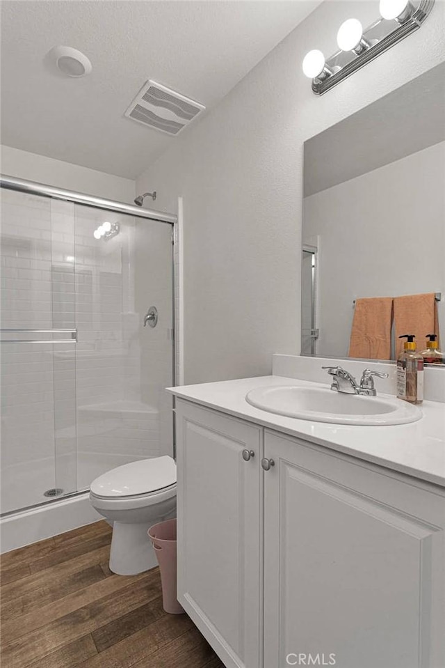 bathroom with hardwood / wood-style flooring, vanity, toilet, and walk in shower