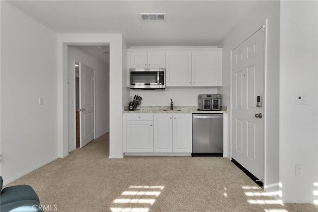 kitchen featuring stainless steel appliances, sink, light carpet, and white cabinets