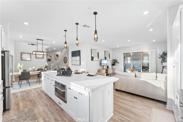 kitchen with pendant lighting, stainless steel appliances, a kitchen island, and white cabinets