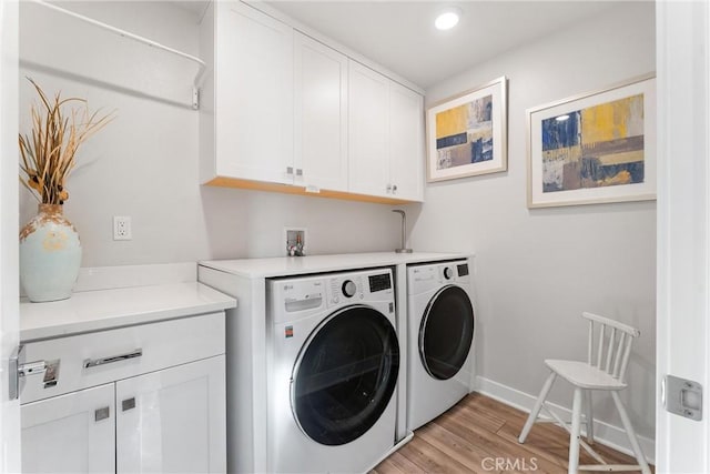 washroom featuring light hardwood / wood-style floors, cabinets, and washing machine and clothes dryer