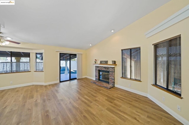 unfurnished living room with ceiling fan, a brick fireplace, lofted ceiling, and light wood-type flooring