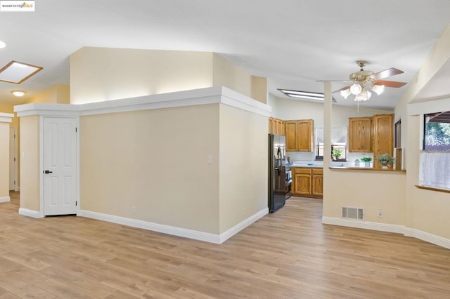 kitchen with high vaulted ceiling, ceiling fan, kitchen peninsula, black fridge with ice dispenser, and light hardwood / wood-style floors