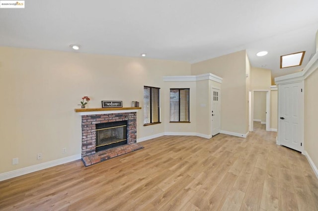 living room with a brick fireplace and light hardwood / wood-style floors