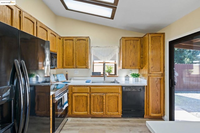 kitchen featuring light wood-type flooring, lofted ceiling, sink, and black appliances