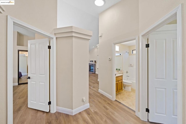 hallway featuring a towering ceiling and light hardwood / wood-style flooring