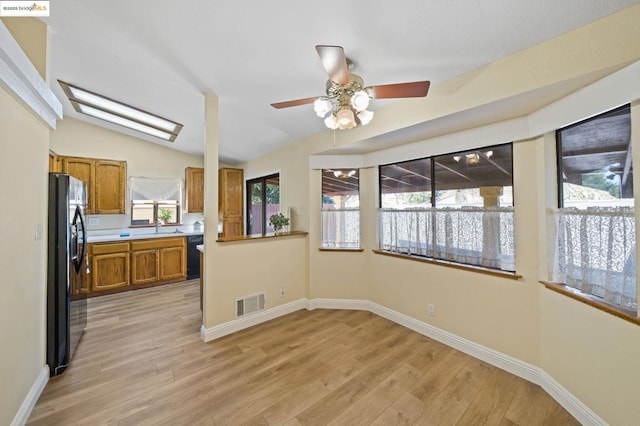 kitchen with vaulted ceiling, black appliances, sink, ceiling fan, and light hardwood / wood-style floors