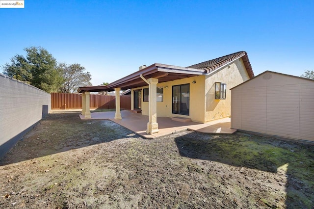 back of property with a storage shed and a patio