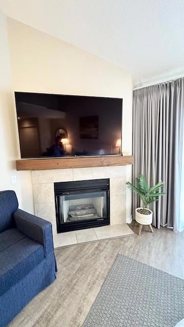 living room with lofted ceiling, hardwood / wood-style floors, and a tile fireplace