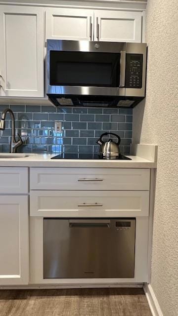 bar with dark hardwood / wood-style flooring, backsplash, sink, and white cabinets