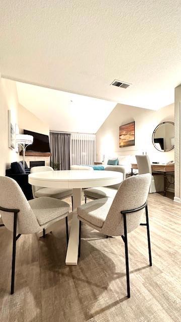 dining room with vaulted ceiling and a textured ceiling