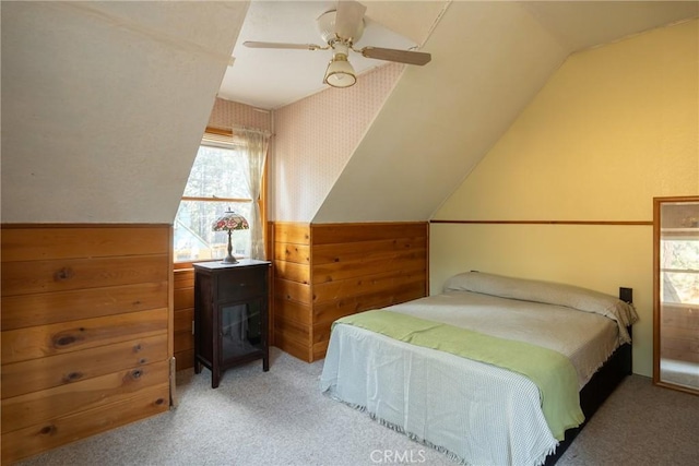 bedroom with light carpet, lofted ceiling, ceiling fan, and wood walls