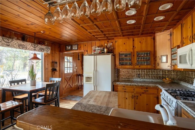 kitchen with wooden walls, decorative light fixtures, sink, wooden ceiling, and white appliances