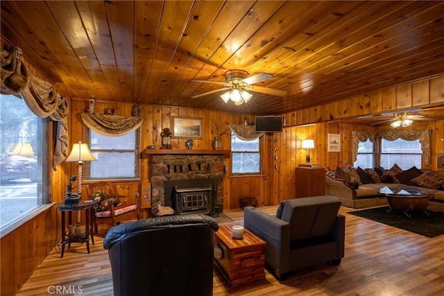 living room featuring hardwood / wood-style floors, a wealth of natural light, wooden walls, and ceiling fan