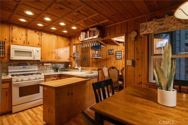 kitchen with sink, light wood-type flooring, wooden ceiling, kitchen peninsula, and white appliances