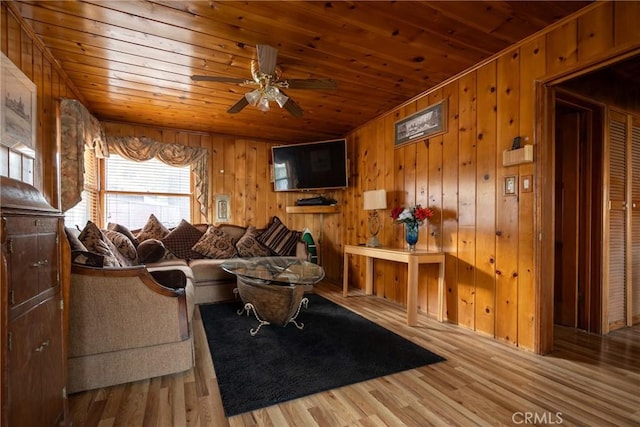 living room featuring wood-type flooring, ceiling fan, wooden ceiling, and wooden walls