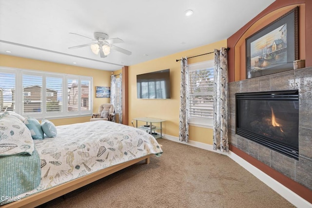 carpeted bedroom with a tiled fireplace and ceiling fan