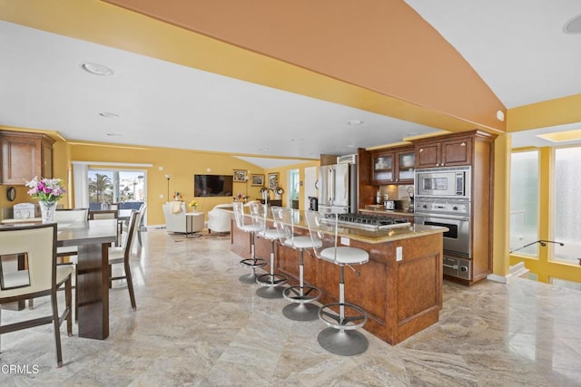 kitchen with a breakfast bar area, vaulted ceiling, stainless steel appliances, and a center island