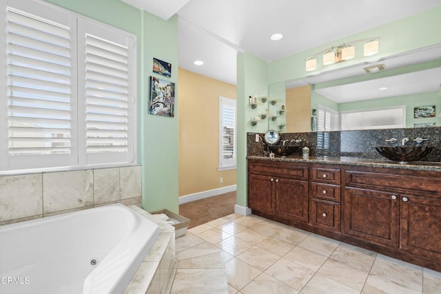 bathroom featuring a relaxing tiled tub, tile patterned floors, a healthy amount of sunlight, and vanity