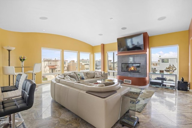 living room featuring a tile fireplace and vaulted ceiling