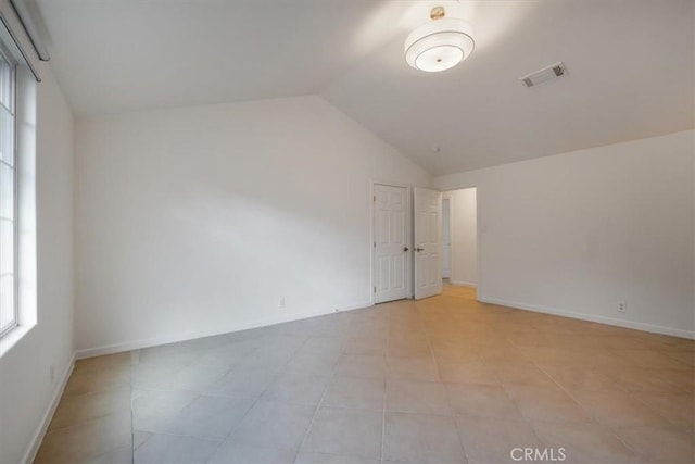 spare room with light tile patterned flooring and vaulted ceiling