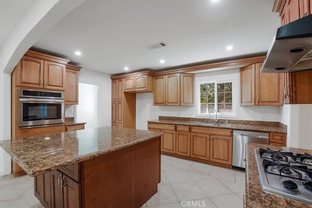 kitchen with appliances with stainless steel finishes, a center island, sink, and stone counters