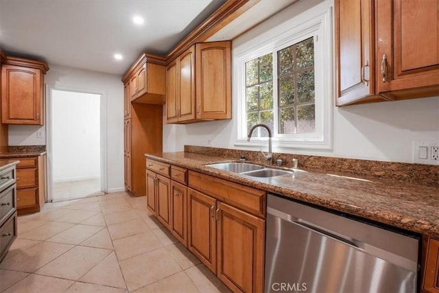 kitchen with sink, stainless steel dishwasher, light tile patterned floors, and dark stone counters