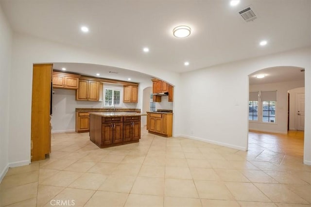 kitchen with plenty of natural light, a kitchen island, and light tile patterned floors