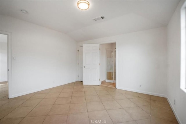 empty room featuring light tile patterned flooring and vaulted ceiling