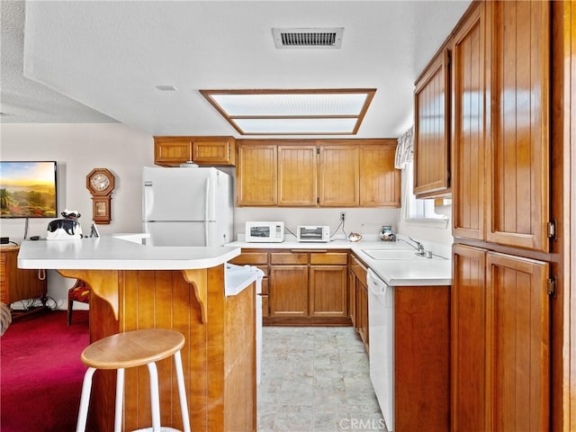 kitchen with sink, white appliances, a center island, and a kitchen bar