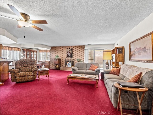 carpeted living room with a brick fireplace, a textured ceiling, and ceiling fan